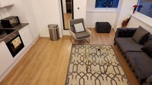 Una sala moderna con un sofá, un tapete estampado, una mesa de centro y una silla.