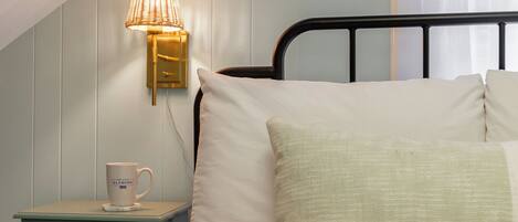 Un dormitorio con cama, mesita de noche, lámpara y ventana con cortinas.