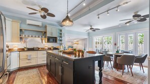 A spacious kitchen with a central island, wooden cabinets, and a dining area with chairs and a table. - GEIGER SUITE @ Inn on Fleming~ADULTS ONLY 2 BR 3rd Floor & Community Pool (Key West)