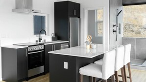 A modern kitchen with a central island, black cabinetry, and a view of the outdoors.
