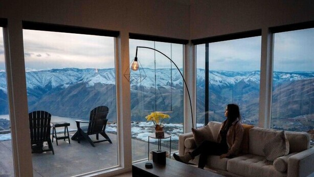 A modern living room with a large glass door leading to an outdoor seating area.