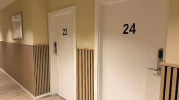 Un pasillo con puertas numeradas 22 y 24, con elementos de diseño moderno como listones verticales de madera y un elegante tirador contemporáneo.