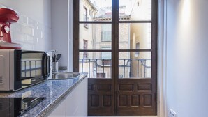 Una cocina con microondas, lavabo y vista a la calle a través de una puerta de madera.