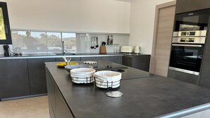 Una cocina moderna con una isla central, electrodomésticos de acero inoxidable y vistas al exterior.