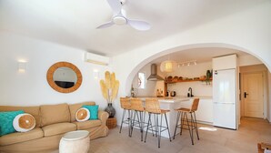 Un salon moderne avec un canapé, une table basse ronde et un coin repas équipé de tabourets de bar.