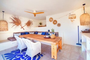 Ein Essbereich mit Holztisch, Korbstühlen, Deckenventilator und dekorativen Wandbildern.