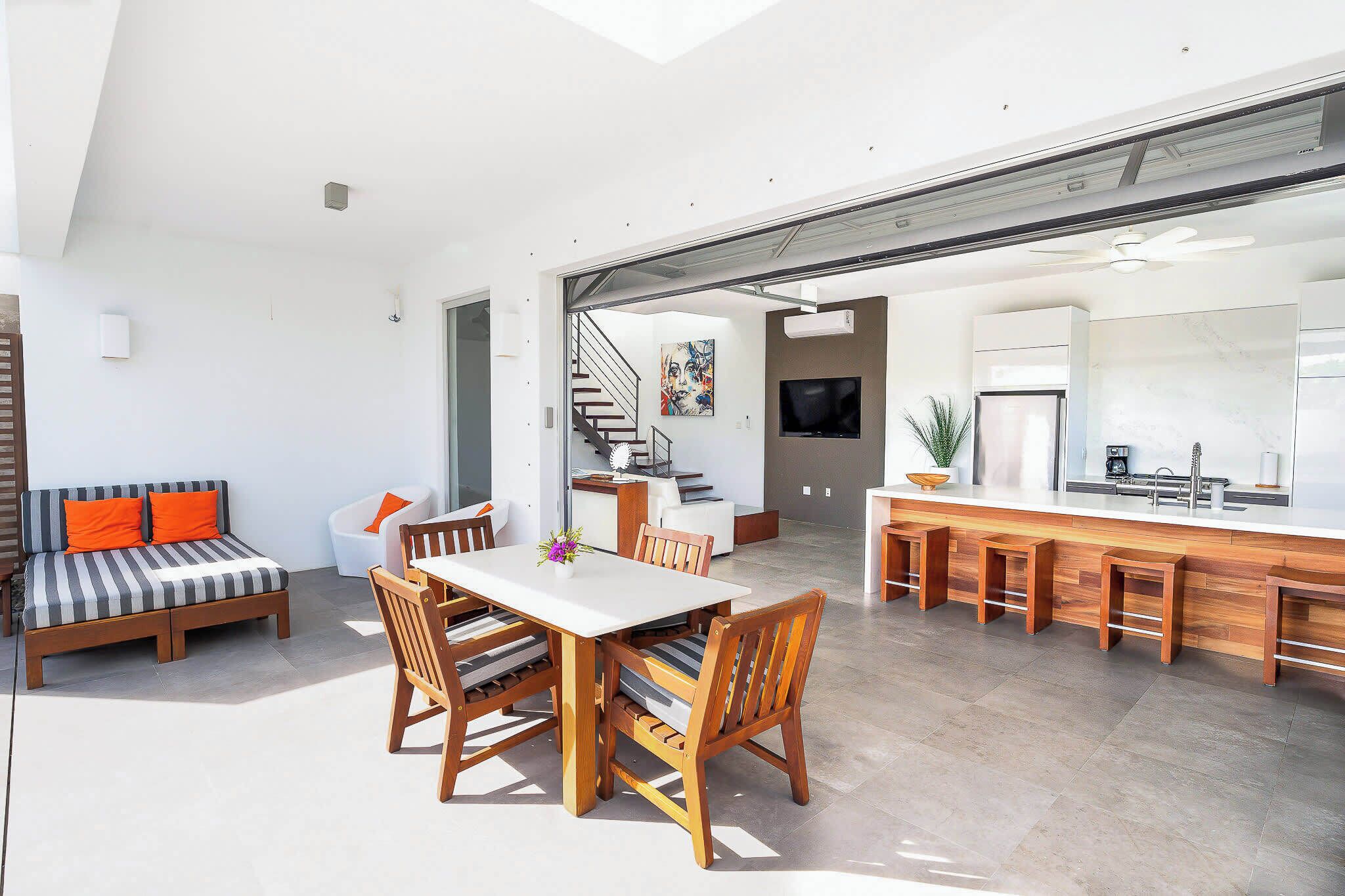 A modern open-plan living space with a dining area, kitchen, and a staircase leading to an upper level.