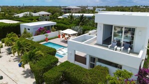 Ein modernes Haus mit Schwimmbad, umgeben von üppiger Vegetation und Palmen.