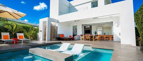 A modern house with a swimming pool, outdoor seating, and a patio area.