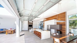 Una cocina moderna con una isla central, taburetes de bar y una mesa de comedor con sillas.