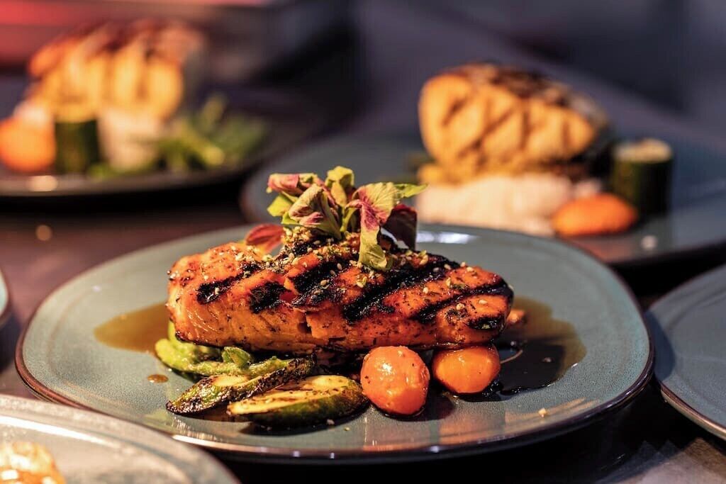 Une assiette de saumon grillé accompagné de légumes.