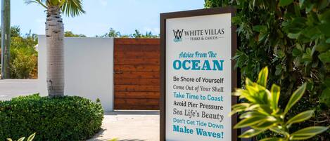 A sign for White Villas with a message about embracing the ocean and its beauty.