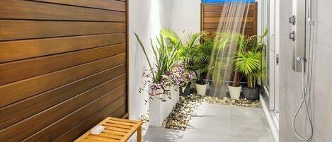 Un baño moderno con ducha, paneles de madera y plantas en macetas.