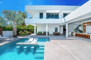 Una casa moderna con piscina, area salotto esterna e angolo cottura.
