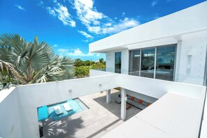 Un edificio moderno con piscina, area relax all'aperto e cielo azzurro.