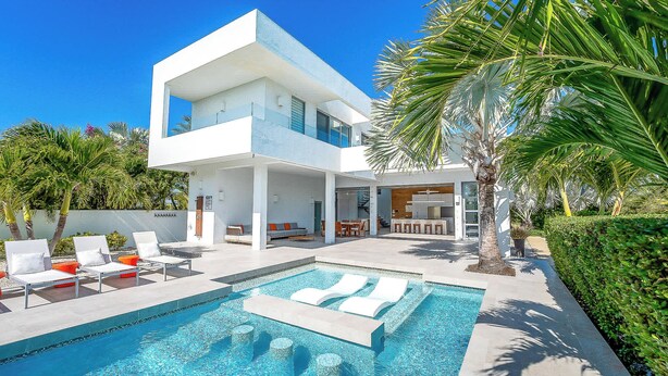 A modern two-story house with a swimming pool, outdoor seating, and palm trees. - Vacation Villa, Oceanview and Hotel Amenities v1 (Providenciales)