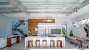A modern kitchen with a central island, bar stools, and a staircase leading to an upper level. - Vacation Villa, Oceanview and Hotel Amenities v1 (Providenciales)