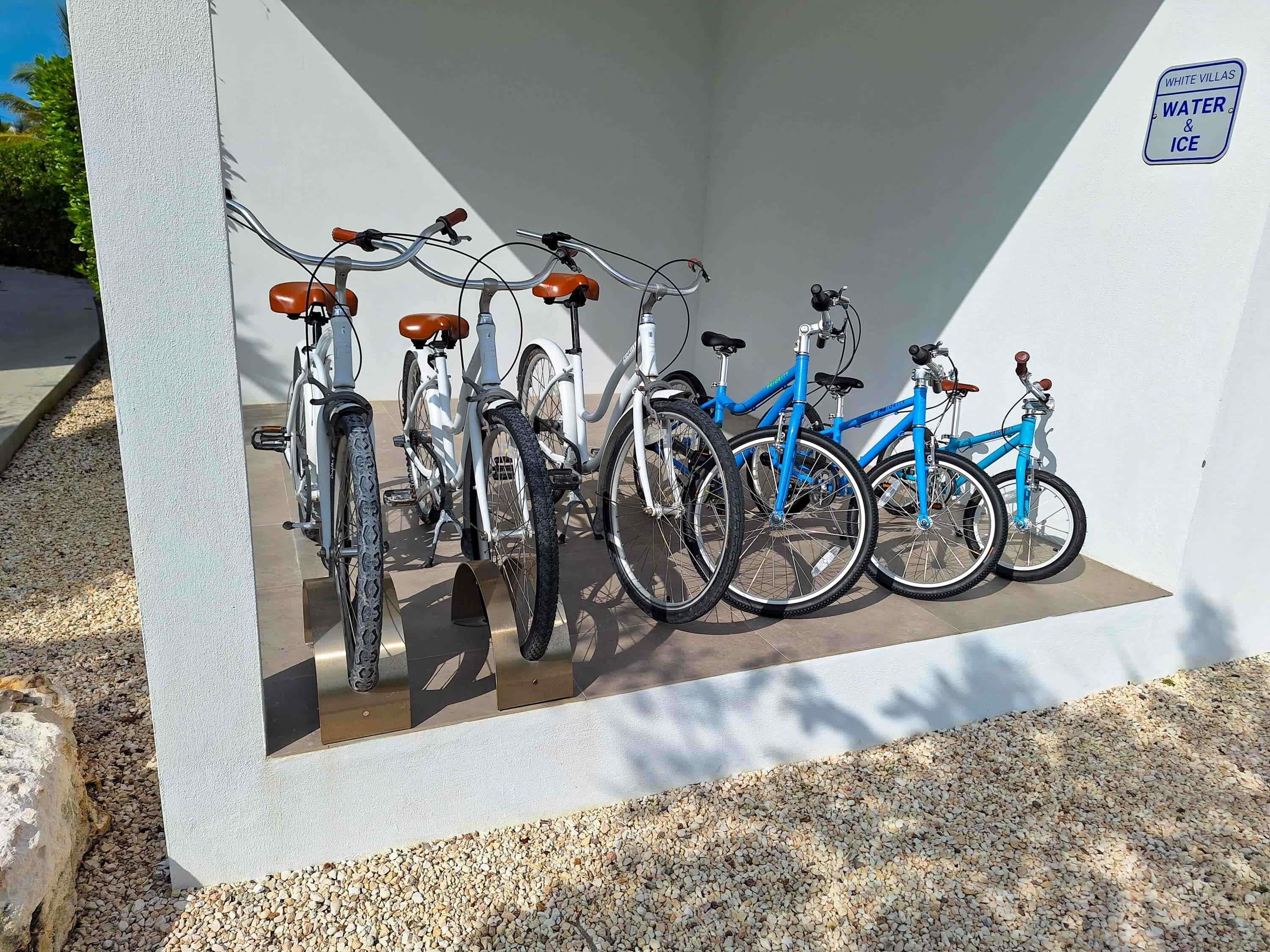 A row of bicycles parked against a wall with a sign indicating water and ice services.