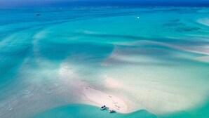 An aerial view of a beach with clear turquoise waters, a sandy beach, and a few boats. - Vacation Villa, Oceanview and Hotel Amenities v1 (Providenciales)