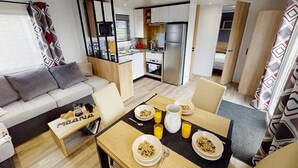 A compact living space with a kitchenette, a dining area with breakfast setup, and a sofa.