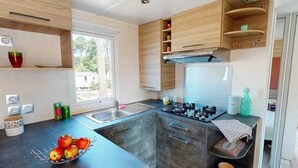 Une cuisine de taille réduite, équipée d’une cuisinière à gaz, d’un évier et de meubles de rangement en bois.