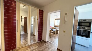 A modern kitchen with built-in ovens and a dining area with a table and chairs. - Apartment Mountain Bliss (Kaprun)