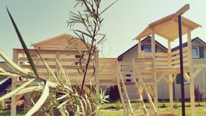 A wooden playhouse with a ladder and a small garden area with plants. - Cozy Cottage in Family Holiday Resort, Jezierzany (Postomino)