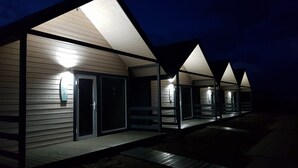 A row of modern, well-lit beach huts with sliding doors and a flat roof, each with a small porch area. - Cozy Cottage in Family Holiday Resort, Jezierzany (Postomino)