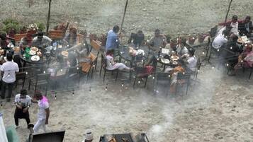Area pranzo all'aperto con diversi tavoli e sedie, immersa in un ambiente sabbioso.
