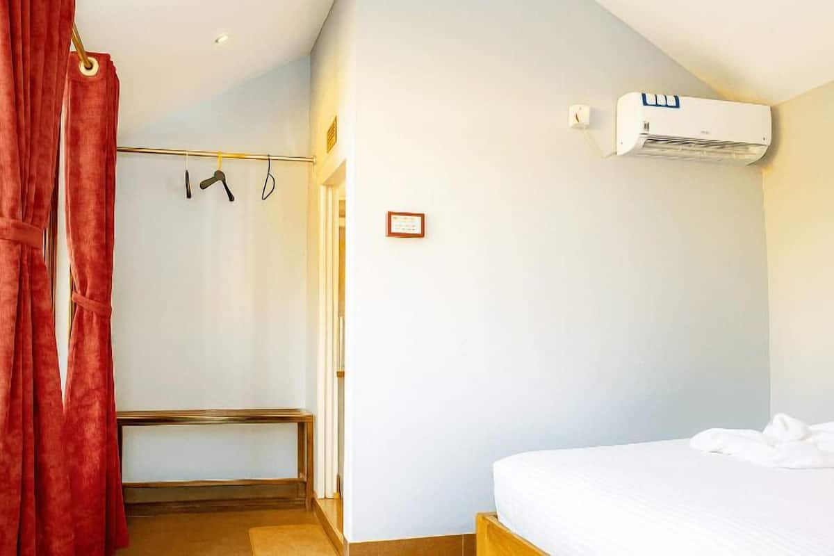 Un dormitorio con cama, aire acondicionado, cortina de ducha y toallero.