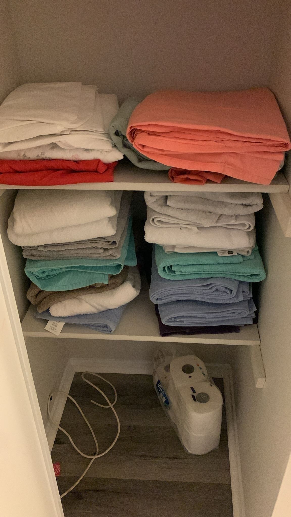 A storage unit with shelves holding folded towels in various colors.