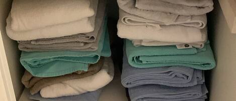 A storage unit with shelves holding folded towels in various colors.