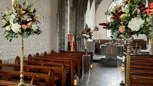 An interior of a church with wooden pews, floral arrangements, and a stone altar. - Summer Sale! Beakstown House Luxurious 5-bed Villa (Holycross)