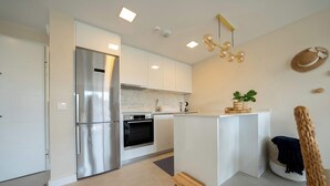 Eine moderne Küche mit Edelstahl-Kühlschrank, Backofen und weißen Schränken.
