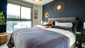 Ein Schlafzimmer mit einem großen Bett, einem Fenster und einer Wanddekoration.