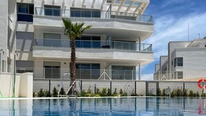 Ein modernes Gebäude mit Pool, Balkonen und einer Palme.