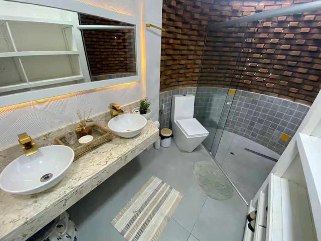Un baño moderno con dos lavamanos, inodoro y zona de ducha.