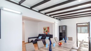 Uma sala de jantar moderna com uma mesa de madeira comprida, cadeiras acolchoadas e um arranjo central com um frasco azul.