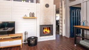 A living room with a fireplace, a television, and a dining area with a table and chairs. - 6 Person Holiday Home in Aabenraa-by Traum (Aabenraa)