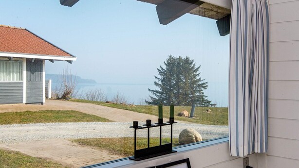 A room with a window overlooking a gravel path, a building, and a tree. There are framed pictures on the wall. - 6 Person Holiday Home in Aabenraa-by Traum (Aabenraa)