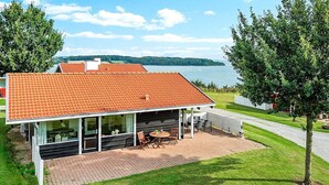A modern house with a tiled roof, large windows, and a patio with outdoor furniture. - 6 Person Holiday Home in Aabenraa-by Traum (Aabenraa)