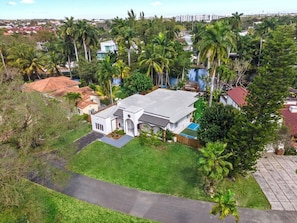 Zona residencial con una casa rodeada de exuberante vegetación y palmeras.