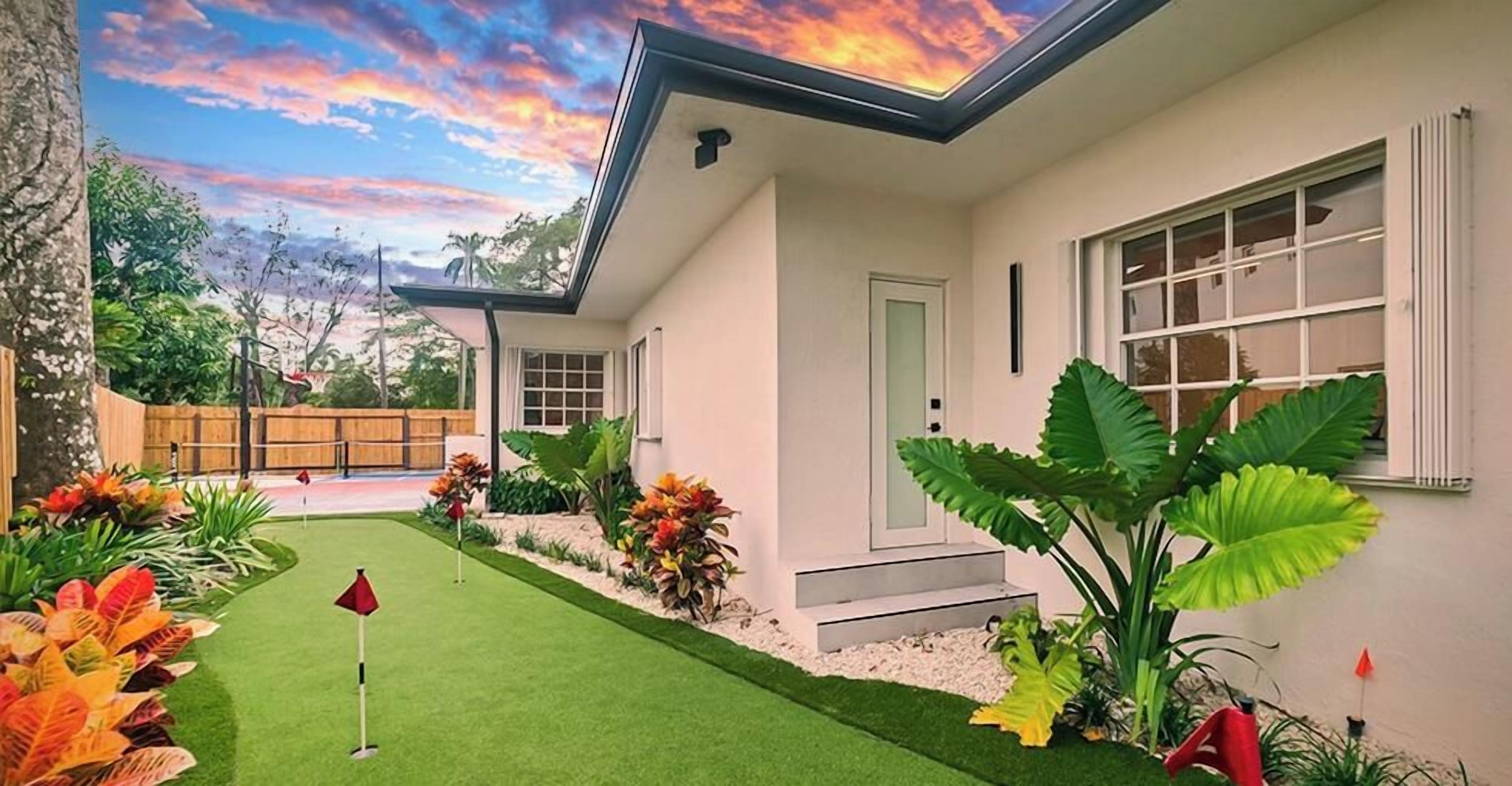 Una casa moderna con césped cuidado, un patio y diversas plantas.