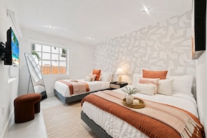 Un dormitorio moderno con dos camas, un ventanal grande y una pared estampada.