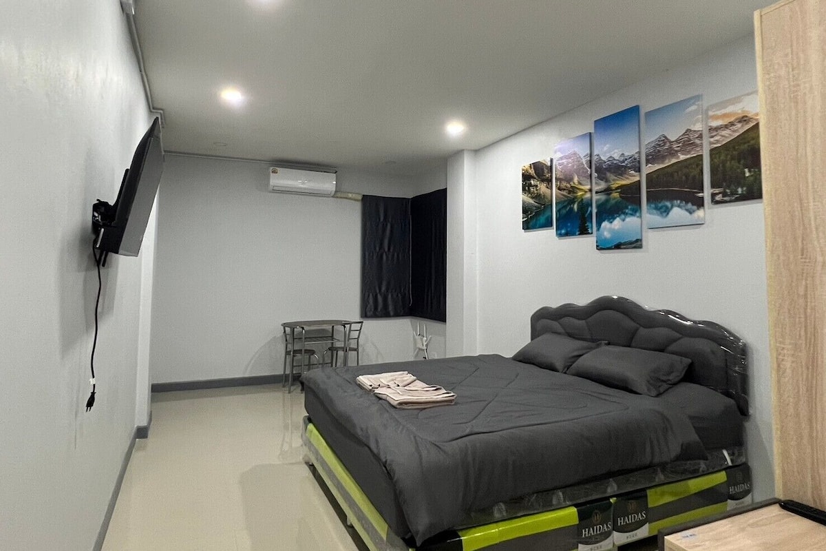 A bedroom with a bed, a desk, and a TV.