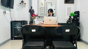 A room with a person working on a laptop at a desk, two chairs, a television on the wall, and a statue on the table. - Civilize apartment (Nonthaburi)