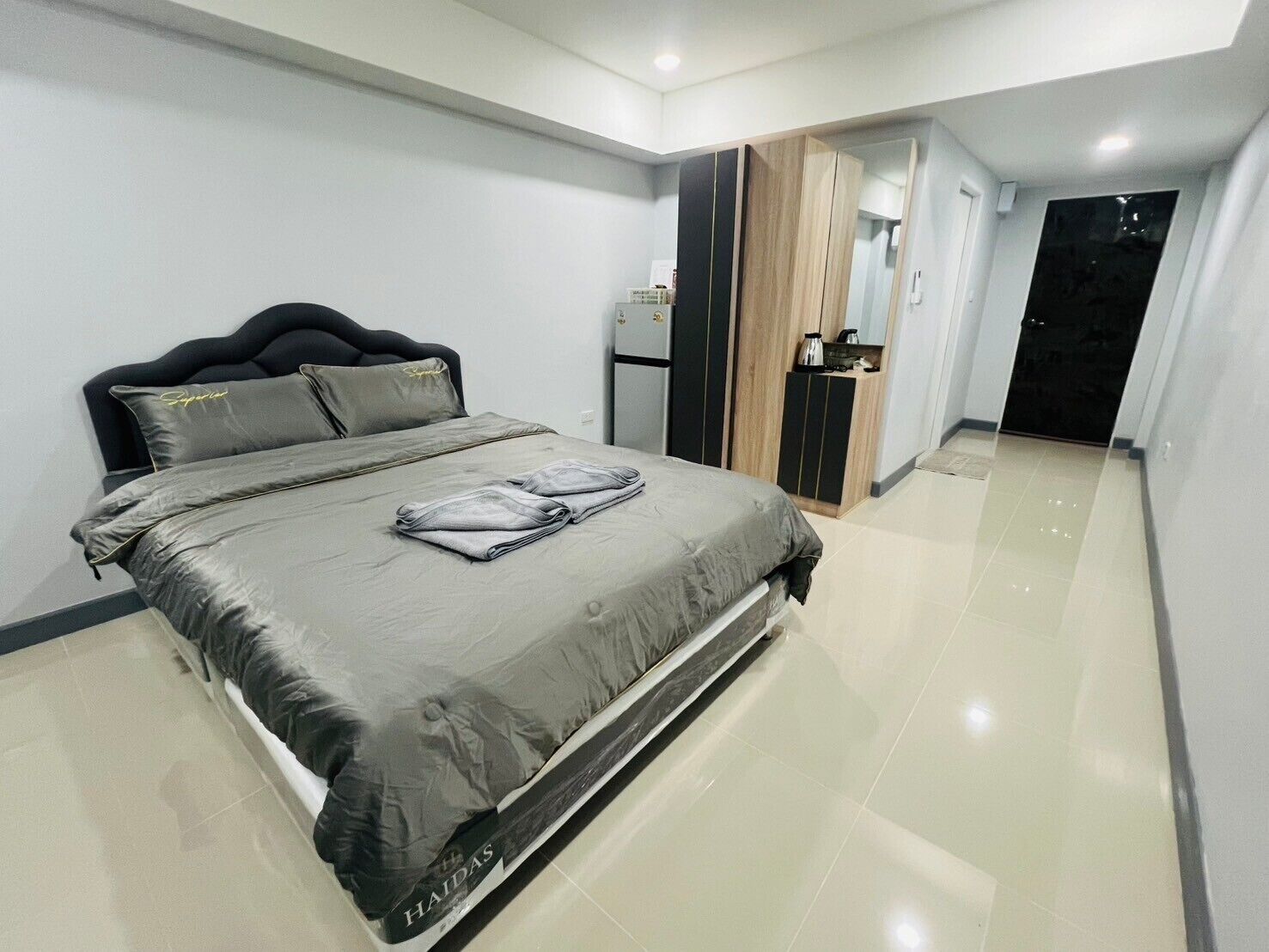 A modern bedroom with a bed, a wardrobe, and a kitchenette.