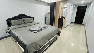A modern bedroom with a bed, a wardrobe, and a kitchenette.