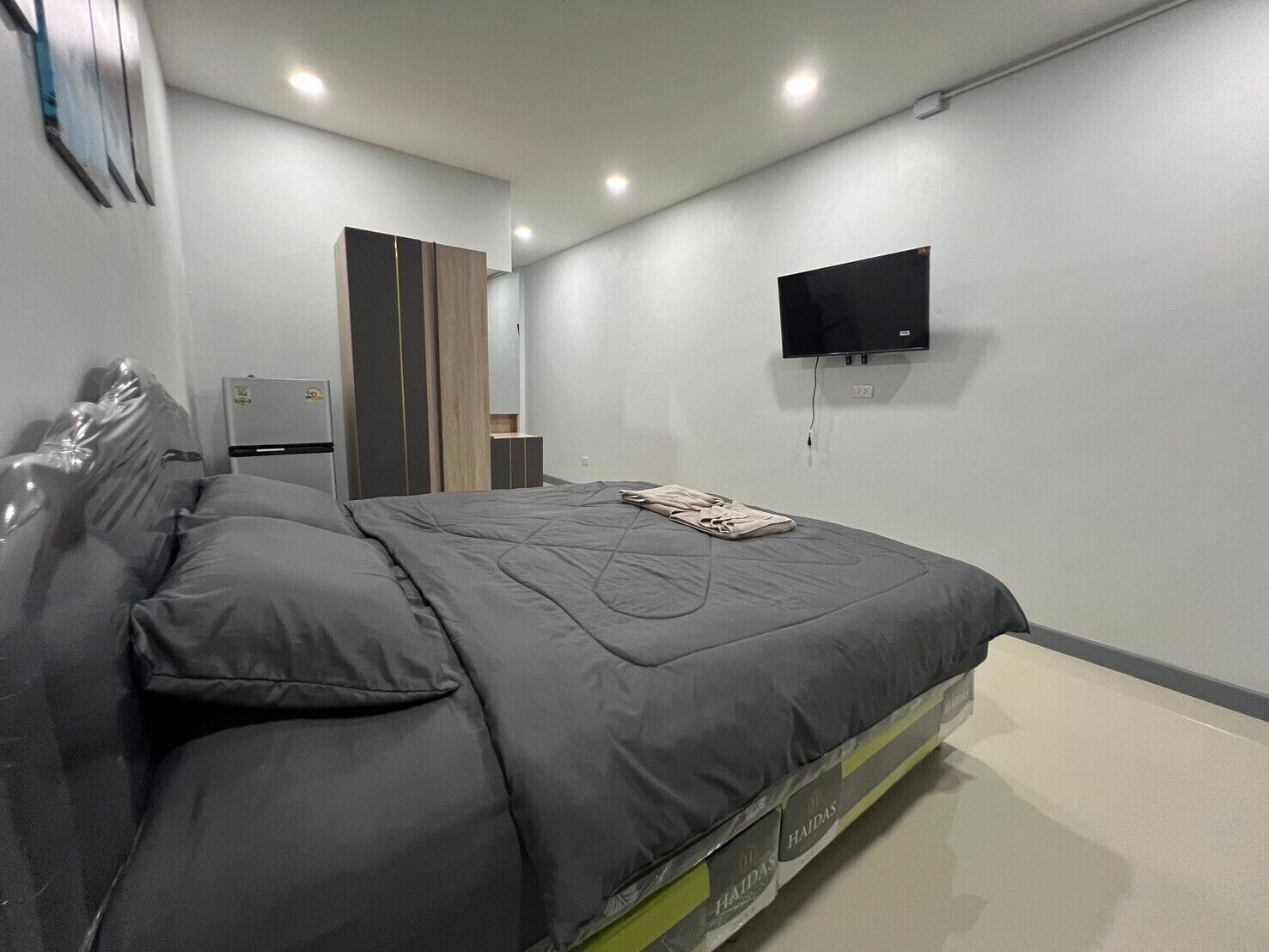 A modern bedroom with a bed, a flat-screen TV, and a wardrobe.