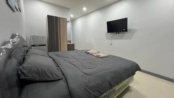 A modern bedroom with a bed, a flat-screen TV, and a wardrobe.